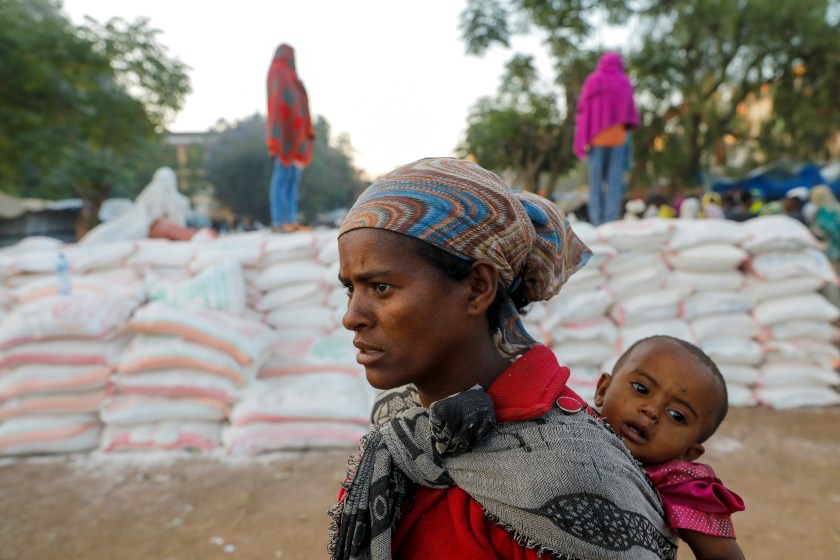 A woman carries an infant as she queues in line for food, at the Tsehaye primary school, which was turned into a temporary shelter for people displaced by conflict, in the town of Shire, Tigray region, Ethiopia, March 15, 2021.   REUTERS/Baz Ratner