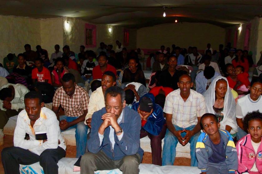 Dr Berhane Asmelash praying at a church in a refugee camp in Ethiopia