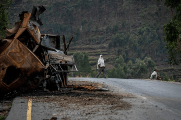 Man crosses road near burnt out tank