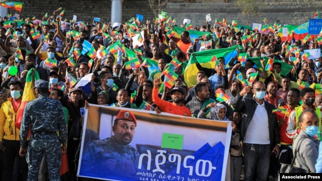 FILE - People gather behind a placard showing Prime Minister Abiy Ahmed at a rally organized by local authorities to show support for the Ethiopian National Defense Force (ENDF), at Meskel square in Addis Ababa, Ethiopia, Nov. 7, 2021.