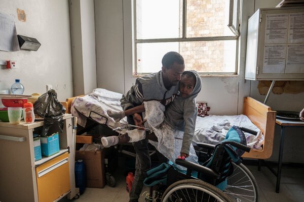 Arsema Berha, 9, being moved into her bed by a relative at Ayder Referral Hospital in the Tigray capital Mekele last month, after being injured during fighting.